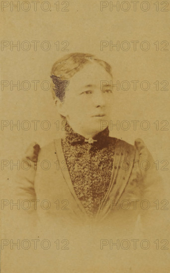 Portrait of a woman from the Marmelstein family, presumably the mother-in-law of AF Marmelstein, photograph, carte-de-visite, inscription: 'Photographie, Parisienne, H. van der Zijl, Nieuwendijk 60, over Raamskooi, Amsterdam., Please note the correct address.', annotation: 'Grandma', photographer: H. van der Zijl, Amsterdam, 1865 - 1900, paper, pasteboard, albumen print, albumendruk, height 104 mm x width 64 mm, historical persons not known by name - BB - woman, A faded sepia portrait of a woman shown from the chest up wearing a high-collared patterned garment and a darker outer layer with gathered shoulders, her hair pulled back and parted at the center, a small decorative element at the neck, and a neutral expression with eyes looking slightly to one side against a plain background.