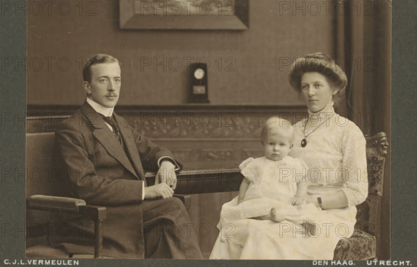 Portrait of an unknown couple and their daughter, cabinet photograph, inscription: 'CJL Vermeulen, Studio for modern photography, The Hague, Toussaintkade 11, Telephone 1873., Utrecht, Nieuwegracht 50, Telephone 750.', annotation: 'Rijswijk 1911.', photographer: Cornelis Johannes Lodewicus Vermeulen, Netherlands, 1890 - 1930, paper, pasteboard, daylight collodion silver print, height 108 mm x width 165 mm, historical persons not known by name, historical persons not known by name - BB - woman, child, A sepia-toned portrait of a family seated indoors on carved wooden chairs, showing a man in a dark suit with a high collar and tie sitting on the left, a woman in a light lace dress with a high lace collar and a pendant necklace seated on the right, and a small child in a light frilly dress sitting on the woman’s lap; the man has a neatly trimmed mustache and rests one arm on the chair arm while the other hand is near his knee, the woman has an upswept hairstyle and a composed expression, ...