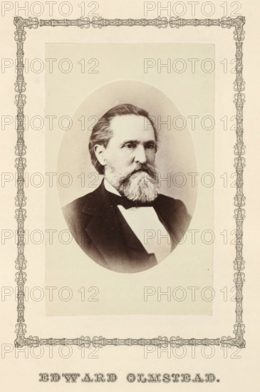 Edward Olmstead, photograph, page, c. 1876 - in or before 1881, photographer, paper, albumen print, height 95 mm x width 58 mm, adult man, A sepia-toned oval portrait of a middle-aged man with neatly combed hair and a full beard and mustache, shown from the chest up wearing a dark suit jacket, a white shirt, and a bow tie, centered on a rectangular pale background with an ornamental decorative border surrounding the portrait area and the page.