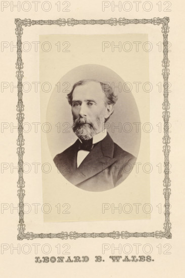 Leonard E. Wales, photograph, page, c. 1876 - in or before 1881, photographer, paper, albumen print, height 95 mm x width 56 mm, Person, Leonard Eugene Wales, magistracy, judges, A sepia-toned oval portrait of a middle-aged man with a beard and mustache, shown from the chest up, wearing a dark suit jacket, a white shirt with a high collar, and a dark bow tie; the portrait is mounted on a pale rectangular backing and surrounded by an ornate decorative border printed on the page.