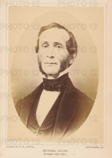 Michael Jacobs, photograph, reproduction, page, photographer: William H. Tipton, Gettysburg, after drawing by anonymous, c. 1877 - in or before 1882, North America, Pennsylvania, paper, albumen print, height 142 mm x width 103 mm, Person, professor, A sepia-toned oval portrait of a middle-aged man shown from the chest up, centered on a pale background with a rectangular border. He has a high forehead with neatly combed hair that parts to one side and rounded sideburns framing his cheeks and jaw. His expression is neutral, with a straight mouth and eyes looking forward. He wears a dark formal jacket over a light shirt with a high collar and a dark bow tied around the neck. The image shows subtle shading and photographic texture, with the edges of the oval fading into the surrounding background.