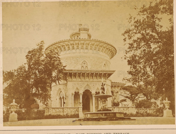 Montserrat-East portico ans terrace, View of a terrace and a portico of the Palácio de Monserrate near Sintra, photograph, page, Portugal, c. 1860 - in or before 1870, photographer, paper, albumen print, height 97 mm x width 132 mm, palace, terrace, gate, entrance, Palácio de Monserrate, A sepia-toned photograph showing a round ornate building with a wide decorative cornice and a smaller circular structure on top, flanked by tall trees; the façade features arched openings with columns, intricate carved patterns, and a balustraded terrace in front; a multi-tiered fountain with a statue stands near the entrance, and stone urns sit on pedestals along the terrace edges.