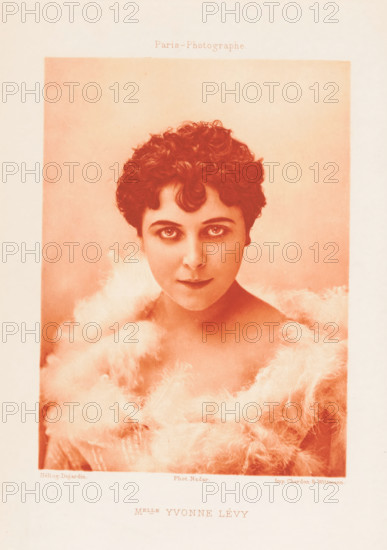 Portrait of Yvonne Lévy, Melle Yvonne Lévy, page, photomechanical print, photographer: Félix Nadar, Paris, cliché maker: Dujardin, printer (person): Chardon-Wittmann, c. 1882 - in or before 1892, printer (person), paper, photoaquatint, height 143 mm x width 106 mm, Person, Yvonne Lévy, portrait of actor, actress, A portrait of a young woman with short curly hair framed in a soft rectangular vignette, shown from the shoulders up and wearing a fluffy, feathery wrap around her shoulders and neck, with large expressive eyes looking toward the viewer and a neutral mouth, rendered in a warm monochrome tone against a plain background.