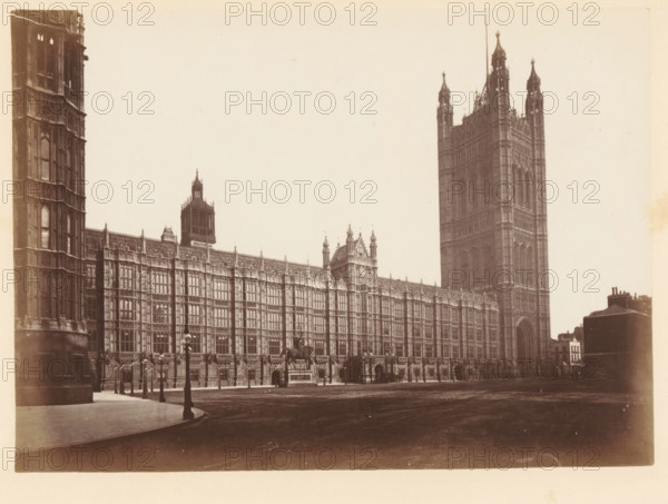 View of Palace of Westminster, south view, photograph, page, photographer: John Harrington, London, c. 1864 - in or before 1869, paper, albumen print, height 141 mm x width 195 mm, palace, Houses of Parliament, A wide sepia photograph of an ornate stone building with a long facade featuring many tall, narrow windows and decorative vertical and horizontal detailing, ending at a very tall, square tower with pinnacles and arched openings, several smaller towers and turrets rising along the roofline, a large arched entrance at the base of the tall tower, a clear paved area and roadway in front, period-style lampposts lining the pavement, a mounted statue on a plinth near the center of the facade, and a smaller cluster of buildings visible at the far right edge.