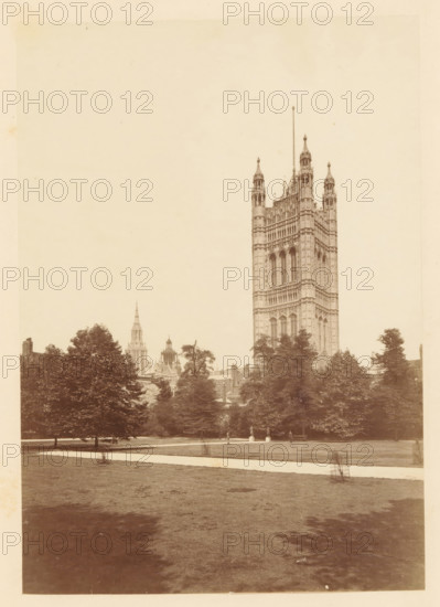 View of Victoria Tower, photograph, page, photographer: John Harrington, London, c. 1864 - in or before 1869, paper, albumen print, height 177 mm x width 124 mm, tower (of house or building), Victoria Tower, A tall ornate stone tower with narrow arched windows and decorative pinnacles rises behind a line of leafy trees, visible against a pale sky; smaller spires and rooflines of additional buildings appear left of the main tower, while a grassy foreground with a light-colored path stretches toward the viewer and includes a small wire protective cage around a young tree and a few indistinct figures near the tree line.