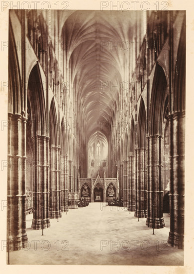 The nave in Westminster Abbey, looking east, photograph, page, photographer: John Harrington, c. 1864 - in or before 1869, paper, albumen print, height 188 mm x width 131 mm, interior of church, abbey, monastery, convent, Roman Catholic church, parts of church interior: nave, London, Westminster Abbey, A tall, vaulted interior with a long central aisle flanked by rows of massive stone columns and pointed arches, the ceiling forming a ribbed series of curved vaults that converge toward a distant, illuminated window; ornate carved screens and sculptural elements sit at the far end of the aisle, with seating and decorative fixtures along the sides, and a patterned stone floor stretching forward from the foreground.