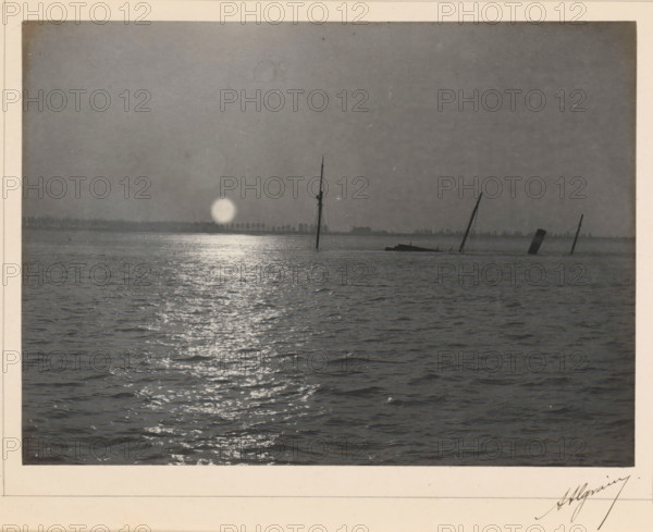 View of a sinking ship with a setting or rising sun, photograph, page, signature: 'Algrain', photographer: Alfred Algrain, c. 1885 - in or before 1890, paper, platinum process, height 158 mm x width 118 mm, landscapes with waters, waterscapes, seascapes (in the temperate zone), ships (in general), sun as celestial body, A grayscale photograph showing a wide expanse of water with rippling surface and a bright reflective path leading toward the horizon, where a low distant shoreline is visible. Near the horizon there are several partially submerged ship masts and a slanted smokestack emerging from the water, silhouetted against a pale circular light near the waterline. The sky above is plain and uniformly shaded, and the image is bordered by a light-colored matte.