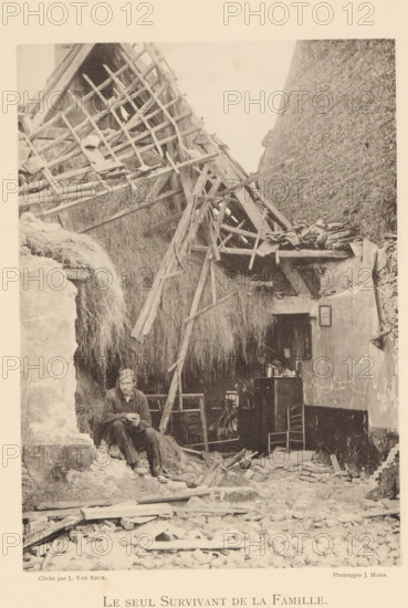 Le seul survivant de la famille, Man in a destroyed house after an explosion of a munitions factory in Oosterweel near Antwerp in 1889, page, photomechanical print, number: '12', photographer: L. van Neck, Oosterweel, cliché maker: anonymous, Belgium, printer (person): J. Maes (possibly), Antwerp, 1889, printer (person), paper, collotype, photoprint, height 230 mm x width 165 mm, Image on page 12., ruin of a building, architecture, Explosion of a munitions factory in Oosterweel in 1889, A sepia-toned scene shows a partially collapsed thatched structure with broken wooden beams and latticework leaning inward and strewn across a large mass of straw or hay; debris and rubble cover the foreground while a man sits on a rough stone ledge near the left, wearing a cap and simple clothing and holding his hands together, with a somber posture; behind and to the right of him an interior space is visible with a small table or cabinet holding assorted vessels and objects, a chair pushed against a w...