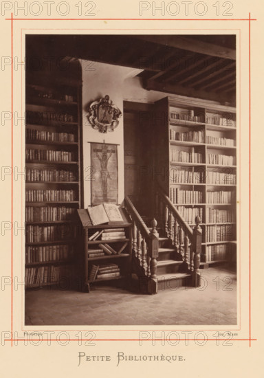 Interior of the library in the house of Christoffel Plantijn, Petite bibliothèque, page, photomechanical print, maker: Joseph Maes, Antwerp, c. 1873 - in or before 1878, paper, Woodburytype, height 164 mm x width 118 mm, study, 'studiolo', library, A sepia photograph shows an interior with tall bookshelves filled with books on either side of a wooden doorway, a carved wooden staircase with turned balusters and newel posts leading up beside the doorway, a small open bookrest holding an open book and additional books on its shelves, a framed image of a crucifix hanging on the wall between the shelves, a decorative crest mounted above the image, exposed wooden ceiling beams overhead, and a tiled floor in the foreground.