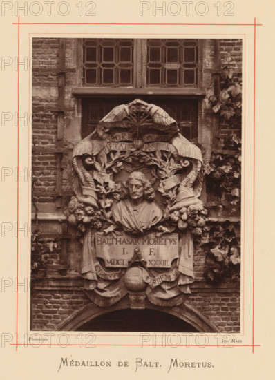 Bust of Balthasar (II) Moretus, Médaillon de Balt. Moretus, page, photomechanical print, maker: Joseph Maes, Antwerp, c. 1873 - in or before 1878, paper, Woodburytype, height 164 mm x width 118 mm, Person, Balthasar Moretus (II), chest, bust, A sepia-toned photograph shows a detailed stone relief mounted on a brick wall beneath a multi-pane window, featuring a carved bust of a man with shoulder-length hair and draped clothing centered within an ornate surround of scrolls, leaves, garlands, floral clusters, and stylized horns; two large wings curve over the top of the relief and a globe with drapery appears below the bust, all framed by climbing foliage and wooden trellis elements against weathered masonry.