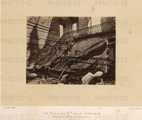 The Palace of St. Cloud Burned. Interior of the Empress's Staircase, View of the Empress's staircase in the Château de Saint-Cloud after the fire caused by the Paris Commune, photograph, page, address: '31, Rue St. Lazare', number: '(No. 62)', photographer: Alphonse-Justin Liébert, Saint-Cloud, 1871 - 1872, paper, albumen print, height 99 mm x width 131 mm, stairwell, ruin of a building, architecture, castle, Paris Commune (1871), Château de Saint-Cloud, A sepia photograph shows a ruined interior with twisted ornate metal stair railings collapsing amid rubble and broken stone fragments, a partially intact carved wall with decorative reliefs and moldings on the left, a large rectangular window opening with shutters on the right, crumbling masonry and fallen architectural elements scattered on the floor, and a pale surrounding border framing the image.