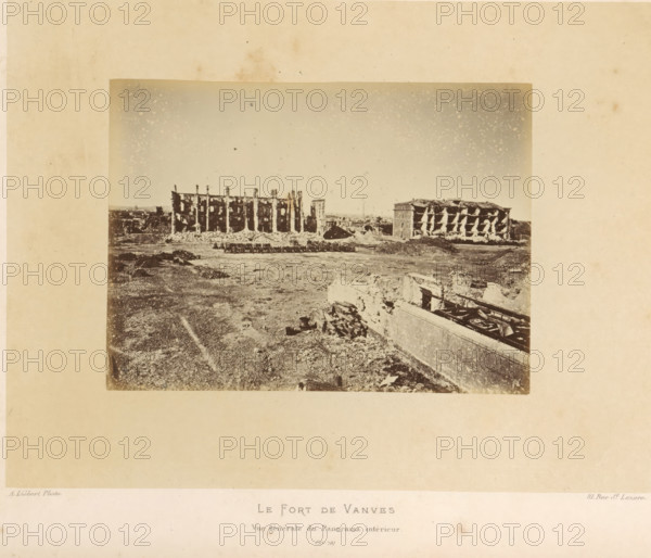 View of Fort de Vanves in Vanves after the destruction by the Paris Commune, Le Fort de Vanves. Vue Générale du Panorama intérieur, photograph, page, number: '(No. 78)', address: '31, Rue St. Lazare', photographer: Alphonse-Justin Liébert, Vanves, 1871 - 1872, paper, albumen print, albumendruk, height 99 mm x width 135 mm, ruin of a building, architecture, fortress, Paris Commune (1871), Fort de Vanves, A sepia-toned photograph of a wide open area with ruined buildings along the horizon, showing two large multi-story structures with exposed interiors and damaged facades, piles of rubble and debris scattered in front of them, a flat foreground of dirt and uneven ground with scattered fragments and low walls, and a partially collapsed structure with visible beams and rubble in the lower right corner under a sky lightly speckled with spots.
