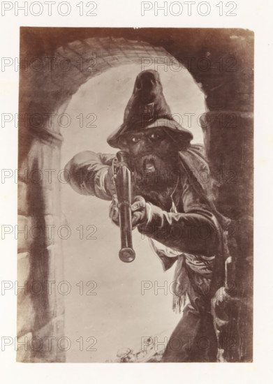 Photo reproduction of Calabrian highwayman by Antoine Wiertz, photograph, reproduction, page, check stamp: 'SOCIÉTÉ ROYALE BELGE DE PHOTOGRAPHIE, 69, RUE KEYENVELD, BRUXELLES', photographer: Edmond Fierlants, after painting by Antoine Joseph Wiertz, c. 1863 - in or before 1868, paper, albumen print, albumendruk, height 150 mm x width 105 mm, robber, A sepia-toned illustration of a bearded man wearing a floppy hat and heavy clothing leaning forward through a stone archway while pointing a long-barreled firearm directly outward, his eyes visible beneath the hat, one hand gripping the barrel and the other on the stock, with folds and tassels on his garments and a partially visible stone wall beside him.