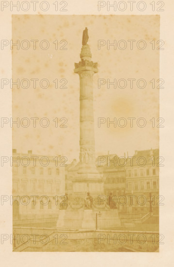 View of the Congress Column in Brussels, photograph, page, check stamp: 'RADOUX, IMPRIMERIE, PHOTOGRAPHIQUE, BRUXELLES', photographer: Louis-Gilbert Radoux, Brussels, c. 1854 - in or before 1859, paper, albumen print, height 181 mm x width 112 mm, Photo opposite title page., column, pillar, architecture, Congress Column, A tall stone column rises from a sculpted pedestal in a city square, topped by a cloaked standing figure; the pedestal features carved reliefs and seated statues around its base. Surrounding the monument are multi-story classical buildings with rows of windows and decorative facades. A stone balustrade and steps lead down from the foreground toward the base of the column, and a street lamp is visible near the pedestal. The image has an overall aged, sepia-toned appearance with scattered foxing and faint spots across the surface.