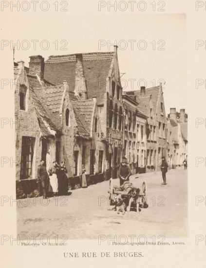 View of a street in Bruges, Une Rue de Bruges, page, photomechanical print, photographer: Alfred Algrain, Bruges, cliché maker: Dero, Frères, Antwerp, c. 1888 - in or before 1893, paper, collotype, photoprint, height 150 mm x width 115 mm, adult man, dog, street, A narrow cobblestone street lined with rows of old brick buildings featuring steep tiled roofs and gabled facades, several window openings and doorways visible along the row, a group of people standing near the front of the buildings wearing period clothing, a man seated behind a small cart pulled by two dogs positioned in the foreground, another person standing further down the street, chimneys and rooftop details visible against a bright sky.