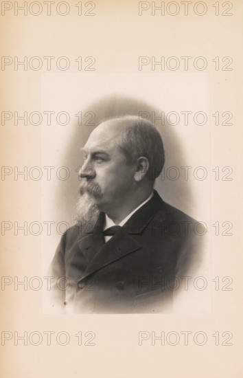 Portrait of Édouard Remouchamps, photograph, page, c. 1883 - in or before 1888, photographer, paper, platinum process, height 141 mm x width 100 mm, Photo opposite title page., Person, Édouard Remouchamps, historical persons, A sepia-toned portrait of an older man shown in profile facing left, with a receding hairline and short hair, a thick mustache and a long pointed beard, wearing a dark formal jacket with a visible collar and a tie, set against a softly shaded oval vignette on a pale background.