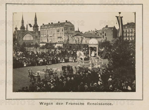 Wagon of the French Renaissance, photograph, page, Antwerp, c. 1899, photographer, paper, printing, height 98 mm x width 152 mm, civic architecture, edifices, dwellings, animal traction, animal-drawn vehicle (carriage etc.), festivities (decorated float, wagon, festive activities), A sepia-toned street scene shows a crowded public square with a large ornate parade float drawn by teams of horses and surrounded by people wearing period clothing and hats. The float features sculptural figures, decorative pillars, and a domed canopy with draped fabric, and a seated figure is visible beneath the canopy. In the foreground a dense crowd lines the cobbled street, with many individuals holding umbrellas and wearing dark coats and wide-brimmed hats. Behind the crowd rows of multistory buildings with varied façades rise along the square, including a building with two tall spires and an arched entrance and other structures with decorative rooflines and awnings. Flags and banners hang from poles an...