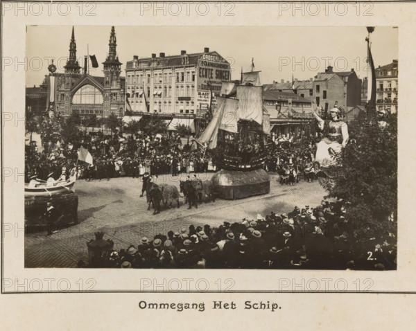 Ommegang the ship, photograph, page, Antwerp, c. 1899, photographer, paper, printing, height 98 mm x width 154 mm, civic architecture, edifices, dwellings, animal traction, animal-drawn vehicle (carriage etc.), festivities (decorated float, wagon, festive activities), A large street scene shows a crowded parade with many people lining cobbled streets and balconies, spectators wearing hats filling the foreground and midground. Decorative floats move along the street, including a large ship-like float with tall sails and rigging, and another float resembling a seated figure in ornate costume raising one arm. Costumed participants accompany the floats, some riding decorated animals harnessed in pairs, and others walking beside the displays. Behind the crowd are multi-story buildings with ornate facades and towers, shopfronts, awnings, and flags displayed on poles. Trees and ornamental lamp posts are visible near the street, and portions of the scene are framed by darker foliage at the rig...