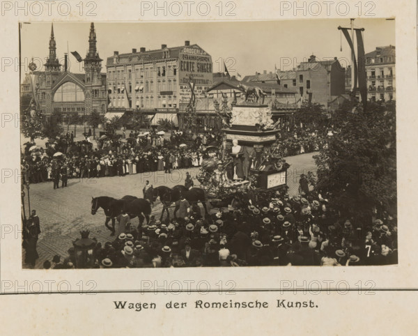 Wagon of Roman art, photograph, page, Antwerp, c. 1899, photographer, paper, printing, height 98 mm x width 152 mm, civic architecture, edifices, dwellings, animal traction, animal-drawn vehicle (carriage etc.), festivities (decorated float, wagon, festive activities), A crowded street scene shows a large ornate float pulled by horses moving through a densely packed throng of people wearing hats and coats, many holding parasols, with a corner of the float featuring sculpted figures and a bust and decorative reliefs; behind the crowd there are multi-story buildings with decorative facades, a large building with tall spires and an arched window, a row of storefronts with awnings, and flagpoles with banners; trees and lamp posts punctuate the scene and people line the sidewalks and upper windows overlooking the procession.