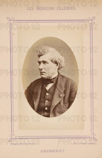 Portrait of Louis Denis Jules Gavarret, Gavarret, photograph, page, inscription: '(Publication de la Revue de literature médicale, du, DF Bremond, 20, Passage Saulnier, Paris., No.', photographer: Pierre Petit, c. 1871 - c. 1879, paper, albumen print, height 90 mm x width 56 mm, Person, Louis Denis Jules Gavarret, historical persons, adult man, An oval black-and-white portrait of an older man mounted on a faded beige card with a decorative purple border, showing the man from the chest up in three-quarter profile facing left, with wavy light-colored hair, a serious expression, a dark jacket over a buttoned vest and a bow tie, and faint blemishes and age marks visible on the card and photograph.