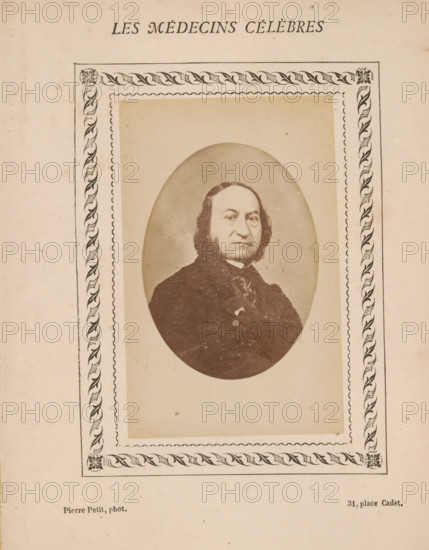 Portrait of an unknown man, photograph, page, inscription: 'Publication de la Revue de literature médicale, du docteur Felix Bremond, 20, Passage Saulnier, 3e année.) - No.', number: '79', photographer: Pierre Petit, c. 1871 - c. 1879, paper, albumen print, albumendruk, height 82 mm x width 51 mm, historical persons, adult man, A sepia-toned portrait of a middle-aged man with a high forehead and dark, shoulder-length hair framing his face, shown from the chest up inside an oval vignette; he wears a dark coat and a necktie with a visible collar and has a neutral facial expression. The oval portrait is set within a rectangular mat bordered by a decorative rope-and-leaf patterned frame with corner floral motifs, all printed on aged, off-white paper with small spots and uneven discoloration.