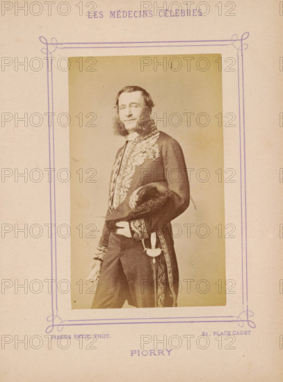 Portrait of Piorry, Piorry, photograph, page, inscription: 'Publication de la Revue de literature médicale, du, ... ) - No.', photographer: Pierre Petit, c. 1871 - c. 1879, paper, albumen print, albumendruk, height 91 mm x width 56 mm, historical persons, adult man, A faded sepia portrait of a man standing three quarters turned, wearing a dark ornate coat with embroidered floral and leaf patterns and decorative cuffs, holding a fur-trimmed hat under one arm and a pair of gloves in one hand, with prominent sideburns and short hair, framed by a simple rectangular border printed on aged paper.