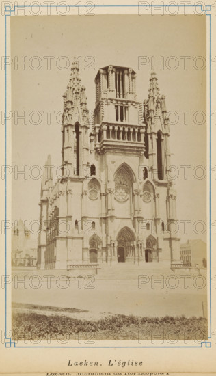 View of the Church of Our Lady in Laeken, Laeken. L'église, photograph, page, Laeken, c. 1875 - c. 1880, photographer, Brussels, paper, albumen print, albumendruk, height 171 mm x width 103 mm, church (exterior), A sepia-toned photograph of a large Gothic-style church façade with twin ornate spires flanking a central tower, pointed arches, carved stonework, circular rose windows, and three arched doorways at the main entrance, set behind a low platform and steps with a grassy foreground and framed by a thin decorative border.