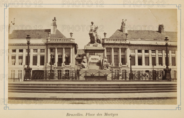 View of the Place des Martyrs in Brussels, Bruxelles. Place des Martyrs, photograph, page, Martelarenplein, c. 1875 - c. 1880, photographer, Brussels, paper, albumen print, height 97 mm x width 172 mm, monument, statue, square, circus, A wide sepia photograph of a neoclassical building facade with a central raised monument surrounded by a decorative iron railing and flanked by ornate street lamps, the monument featuring a seated female figure at the top with drapery and a sculpted lion beside her and two seated female figures at the base, broad stone steps leading up to the railing, tall windows with shutters and decorative cornices on the building behind, chimneys and a sloped roof visible above, and a paved street in the foreground.