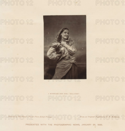 Portrait of an unknown young woman with a water jug, A mountain-dew girl: Killarney, page, photomechanical print, According to page 37, this is an example of the first published examples of the Woodburytype., inscription: 'Printed by Woodbury's Patent Photo-Relief Process, Presented with the Photographic News, January 26, 1866.', photographer: Henry Peach Robinson, printer (person): Walter Bentley Woodbury, 1866 - in or before 1866-01-26, Henry Peach Robinson, Walter Bentley Woodbury, photographer, printer (person), paper, Woodburytype, Woodburytypie, width 89 mm x thickness 60 mm, Print two pages before page 38., adolescent, young woman, maiden, jar, jug (used as drinking-vessel), A sepia-toned portrait centered on a large pale background shows a young woman wearing a headscarf and layered draped clothing, her hair visible at the front of the scarf, with a faint smile and eyes looking slightly to the side; she holds a rounded vessel against her body with one arm while the other hand r...