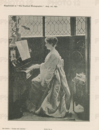Woman playing piano, page, photomechanical print, inscription: 'See Article: 'Posing and Lighting.'', inscription: 'Supplement to 'The Practical Photographer.' Aug. 1st, 1890.', inscription: 'Study No. 1.', c. 1885 - in or before 1890, paper, autotype, height 147 mm x width 114 mm, Print on second unnumbered page after page 182., adult woman, keyboard instruments (artist at work), A monochrome image of a woman seated at a piano, shown in profile facing left, with hands on the keys and sheet music propped on the piano; she wears a long dress with a large bow at the back and a draped fabric that falls to the floor, and her hair is short and curly; behind her is a dark paneled wall and a tall window with diamond-patterned leaded glass, with a vase of flowers visible on a surface near the window; to the right of the woman a tall plant and a small stand holding folded papers or magazines are visible.