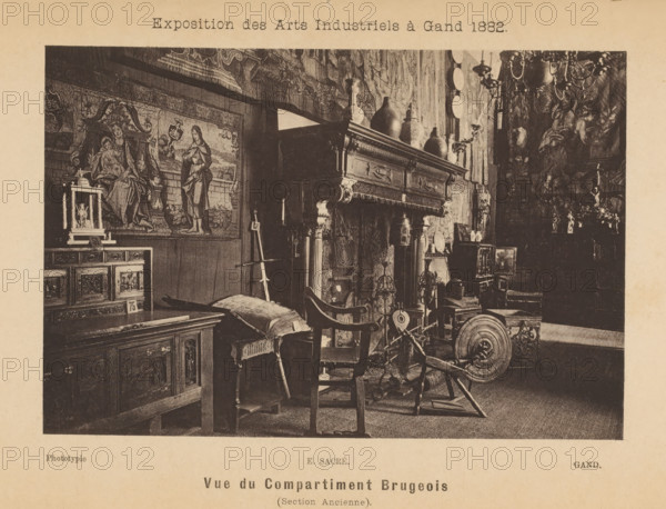 Interior of the Brussels part of the Exposition des Arts Industriels, Vue du compartment Brugeois (section ancienne), page, photomechanical print, inscription: 'Exposition des Arts Industriels à Gand 1882', cliché maker: Edmond Sacré, c. 1878 - in or before 1883, photographer, paper, collotype, photoprint, height 101 mm x width 152 mm, book - MM - book open, open hearth, fire-place, stool, A sepia-toned photograph of a room filled with ornate antique furniture and decorative objects, including a large carved wooden mantel with vases and pitchers arranged on top, a tapestry or painted wall hanging depicting robed figures, a wooden cabinet with carved panels, a cushioned bench, and a spinning wheel among various chairs and small tables; chandeliers and wall-mounted plates are visible on the right, and smaller decorative items and framed pieces sit on surfaces throughout the space.