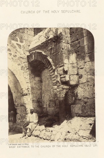 View of west entrance to the Church of the Holy Sepulcher in Jerusalem, West Entrance to the Church of the Holy Sepulchre (Built up), Church of the Holy Sepulchre, photograph, page, photographer: James McDonald, Jerusalem, c. 1860 - in or before 1865, paper, albumen print, height 523 mm x width 340 mm, Photo on page 24., church (exterior), gate, entrance, Zion Gate, A sepia-toned photograph shows a stone architectural scene with a large arched doorway and rough textured masonry. The arch has a series of protruding voussoirs and sits beside a squared column with a carved capital. Stone blocks of varying sizes form the surrounding wall, showing weathered surfaces and irregular joints. Rubble and stones are piled at the base of the wall, and a shallow recess or niche is visible under the arch. A man wearing a light-colored long garment and head covering is seated on the stone rubble near the arch, holding a dark folded cloth on his lap. The image has rounded upper corners and a plain ligh...