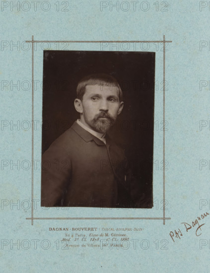 Portrait of Pascal-Adolphe-Jean Dagnan-Bouveret, page, photomechanical print, inscription: 'DAGNAN-BOUVERET (Pascal-Adolphe-Jean), Né à Paris. Elève de M. Gérôme, Med. 3rd. Cl. 1878, 1st. Cl. 1880., Avenue de Villiers, 147, Paris.', signature: 'PAJ Dagnan.', cliché maker: Lemercier (possibly), c. 1879 - in or before 1884, photographer, paper, Woodburytype, Woodburytypie, height 138 mm x width 99 mm, Person, Pascal-Adolphe-Jean Dagnan-Bouveret, historical persons, portrait, self-portrait of painter, A sepia portrait of a man mounted on textured light blue paper with a simple thin rectangular border drawn around the photograph; the man faces slightly to his left with short straight hair and a trimmed mustache and beard, wearing a dark jacket with a visible collar and a light shirt underneath, and the photograph shows a dark background behind him.