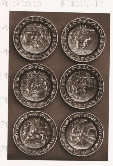 Six enamel signs, set up during the 1873 Exposition Rétrospective in Tours, France, page, photomechanical print, maker: Gabriel Blaise, Tours, 1873, paper, Woodburytype, Woodburytypepie, height 230 mm x width 155 mm, temporary exhibition, 'Salon', dish, plate, saucer, enamelling, applied arts, Period, 1873-05-03 - 1873-05-25, A vertical panel showing six round decorative plates arranged in two columns and three rows against a dark background, each plate featuring an ornate patterned rim and a central engraved scene with human figures and architectural or natural elements; the top left plate shows figures working in a field with tools and bundles, the top right plate depicts two figures near a building and a field with one bending and the other standing with a basket, the middle left plate presents figures around a tub beneath trees, the middle right plate shows two seated figures and one standing figure in an outdoor setting with buildings in the distance, the bottom left plate contain...