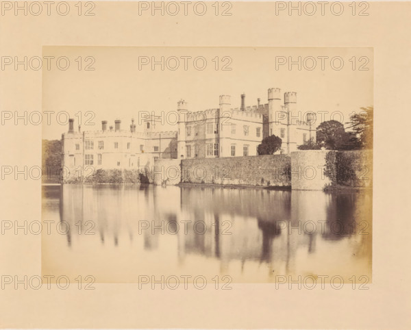 View of Leeds Castle, photograph, page, inscription: 'No.6.', photographer: John Cruttenden, Leeds Castle, c. 1864 - in or before 1869, Leeds, paper, albumen print, height 145 mm x width 201 mm, landscape with tower or castle, walls, fortified city, A wide, faded sepia-toned photograph of a large stone building with battlements and multiple square towers standing beside a body of water, the building reflected in the calm surface; a high stone wall runs along the waterline in front of the building, and trees and shrubbery appear beside and behind the structure; the image is bordered by a lighter margin.