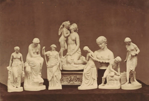 Arrangement of eight sculptures, photograph, This photo is part of a cover with eight photos, two text sheets and a wrapper., annotation: 'Statuettes for the Art Union of London #10', photographer: Howlett & Co. Cundall, c. 1853 - in or before 1858, paper, albumen print, height 146 mm x width 199 mm, piece of sculpture, reproduction of a piece of sculpture, A row of pale sculptures is arranged on a dark surface against a plain darker background, featuring several standing and seated female figures in flowing drapery, a central seated woman with a small winged child perched beside her, a figure holding a staff, a seated bust-like figure on a plinth, a kneeling child beside a seated woman, and a standing woman at one end gently leaning forward, all rendered in a classical style with smooth surfaces and detailed hair and clothing.