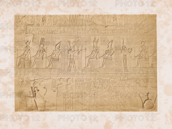 Hieroglyphics on the outer wall of the temple complex at Denderea, Sculptures from the outer wall, page, This photo is part of a cover with 7 pages of albumen prints., inscription: 'Dendera', photographer: Francis Frith, Dendera, 1857, North Africa, paper, albumen print, height 151 mm x width 223 mm, Person, temple, shrine, Egyptian religion, Egyptian hieroglyphs, Dendera Temple complex, A rectangular stone panel with carved figures and decorative bands sits against a mottled light background; the panel shows seated humanlike figures in profile wearing tall headdresses and holding staffs, alternating with standing figures in profile raising arms or holding objects, all rendered in shallow bas relief with detailed headdresses, garments, and stylized limbs; the upper portion contains horizontal registers filled with repeated narrow vertical motifs and small carved animals and symbols, while the lower area displays more compact vertical columns of carved motifs and scenes including a larg...