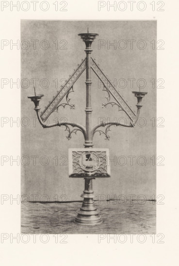 Easter candelabrum from the Saint-Vaast Church in Gaurain-Ramecroix, displayed at an exhibition of religious objects from the Middle Ages and Renaissance in 1864 in Mechelen, page, photomechanical print, number: '6 ...', number: '6', number: '-52', photographer: Joseph Maes, Mechelen, clichémaker: Simonau & Toovey, Antwerp, 1864 - in or before 1866, paper, photolithography, height 225 mm x width 141 mm, chandelier, candelabrum, Easter, Period, 1864, A tall ornate metal stand with a central vertical shaft and a stepped circular base supports branching curved arms and triangular decorative panels with fleur-de-lis and trefoil motifs, ending in shallow cup-like holders with spikes; a square panel with a circular carved emblem is mounted on the shaft above the base.