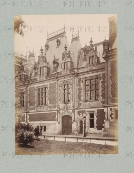 Façade of a residential house in Paris, designed by Jules Février, photograph, This photo is part of a cover with 35 photos and a title page., name: 'Février Architecte', number: '21', photographer: Lampué et Cie, Paris, c. 1875 - in or before c. 1880, paper, albumen print, height 224 mm x width 166 mm, urban housing, façade (of house or building), A sepia-toned photograph of an ornate stone and brick building façade with steeply pitched slate roofs and decorative finials, featuring tall windows with stone mullions and carved surrounds, arched doorways with carved ornamentation, patterned brick panels between stone quoins, carved gables with small dormer windows, intricate balustrades and cresting along the roofline, lamp posts on the pavement in front, a low fence separating a grassy foreground and shrubbery from the sidewalk, and a tree branch visible at the upper left.