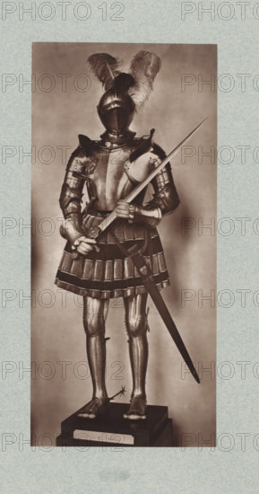 16th-century armor with sword from the army of Francis I of France, from the collection of the Musée d'Artillerie in Paris, photomechanical print, This print is part of a cover with 36 prints, a title page and a list of images., check stamp: 'PHOTOGLYPTIE, LEMERCIER ET Cie, PARIS', Paris, cliché maker: Lemercier & Cie., c. 1877 - in or before 1882, Lemercier & Cie., photographer, cliché maker, paper, Woodburytype, Woodburytypie, height 278 mm x width 131 mm, hacking and thrusting weapons: sword, armour, A full-length photograph of a suit of armor standing on a stepped base, the armor including a closed helmet topped with large plumes, a breastplate with articulated shoulder defenses, segmented fauld and tassets resembling a skirt, articulated arm and leg plates, gauntleted hands holding a long sword with its scabbard hanging at the side, metal sabatons on the feet with a spur visible on one heel, and the entire figure presented against a plain backdrop with a narrow framed border aroun...