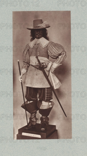 17th-century uniform with sword from the army of Louis XIII of France, from the collection of the Musée d'Artillerie in Paris, photomechanical print, This print is part of a cover with 36 prints, a title page and a list of images., check stamp: 'PHOTOGLYPTIE, LEMERCIER ET Cie, PARIS', Paris, cliché maker: Lemercier & Cie., c. 1877 - in or before 1882, Lemercier & Cie., photographer, cliché maker, paper, Woodburytype, Woodburytypie, height 271 mm x width 123 mm, hacking and thrusting weapons: sword, (military) uniforms, A sepia-toned full-length portrait of a person standing on a wooden pedestal, wearing a wide-brimmed hat with a feather, a lace-trimmed collar over a fitted doublet with puffed, striped sleeves, and a sash tied at the waist; the figure holds a long thin staff in one gloved hand and a sheathed sword hangs at the hip, while the other hand rests on the waist; they wear knee-length breeches tucked into tall leather boots with turned-over tops and decorative spurs, and long h...