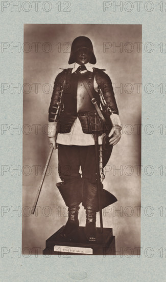 17th-century armor with sword from the army of Louis XIII of France, from the collection of the Musée d'Artillerie in Paris, photomechanical print, This print is part of a cover with 36 prints, a title page and a list of images., check stamp: 'PHOTOGLYPTIE, LEMERCIER ET Cie, PARIS', Paris, cliché maker: Lemercier & Cie., c. 1877 - in or before 1882, Lemercier & Cie., photographer, cliché maker, paper, Woodburytype, Woodburytypie, height 270 mm x width 139 mm, hacking and thrusting weapons: sword, armour, A full-length photograph of a mannequin dressed in historical armor and clothing standing on a plinth, wearing a rounded helmet that obscures the upper face and a breastplate over a light-colored shirt with a wide collar, layered shoulder and arm armor with visible straps and rivets, a sash worn across the chest, a waist pouch and belt with hanging straps, dark knee-length breeches tucked into tall folded-over boots, one hand holding a straight staff and the other resting on a curved o...