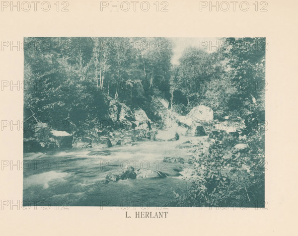 Landscape with rapids, Sentiment d'Art en Photographie, photomechanical print, This print is part of 8 covers with 22 text sheets and 89 prints on loose sheets in and between the covers., number: 'Vol. 1, No 1, Planche 5.', photographer: Léon Herlant, clichémaker: anonymous, printer (person): Liorel & Cie., c. 1893 - in or before 1898-10, Léon Herlant, Liorel & Cie., photographer, clichémaker, printer (person), paper, collotype, light print, height 151 mm x width 215 mm, rapids, A rectangular, blue-tinted image of a river scene centered on a pale background, showing flowing water in the foreground with visible currents and smooth rocks partially submerged, a rocky riverbank with larger boulders and scattered stones, dense trees and foliage rising behind the rocks with visible trunks and leafy canopies, and vegetation along the right edge extending into the frame.