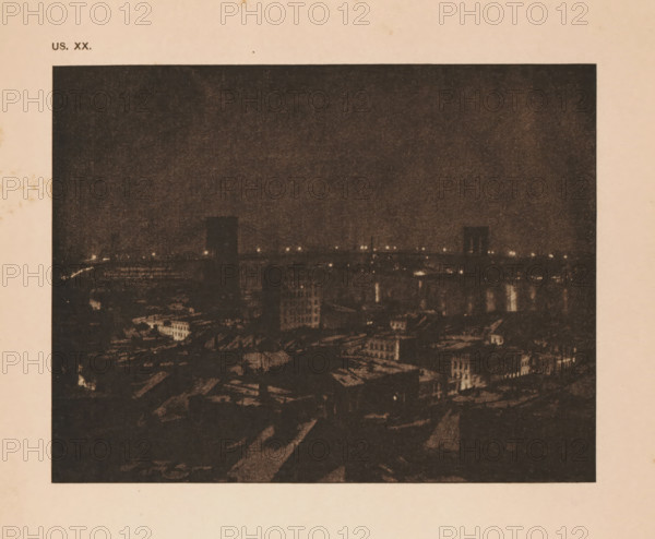 View of New York with the Brooklyn Bridge, page, photomechanical print, inscription: 'US. XX.', inscription: 'The bridge by JF Strauss', photographer: John Francis Strauss, cliché maker: anonymous, c. 1900 - in or before 1905, paper, autotypie, height 112 mm x width 146 mm, city-view in general, 'veduta', bridge in city across river, canal, North America, New York (city), Brooklyn Bridge, A dark, grainy nighttime cityscape framed by a light border, showing a skyline with dimly lit buildings and a river reflecting scattered points of light, with several faintly illuminated structures rising above lower rooftops and a mostly dark sky occupying the upper area.