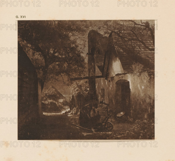 Farm, page, photomechanical print, inscription: 'G. XVI.', inscription: 'A quiet retreat by Karl Prokop', photographer: Karl Prokop, cliché maker: anonymous, c. 1900 - in or before 1905, paper, two-color autotype, height 106 mm x width 122 mm, A sepia-toned scene shows a narrow outdoor passage flanked by buildings with sloped roofs and a variety of trees and foliage, a large tree canopy dominates the left side while a smaller tree branch stretches across the upper right; a wooden beam projects from one building toward the center, and a small arched doorway is visible on a building wall; the ground appears uneven with a curved object lying on it and darker shadows in the foreground, while lighter tones suggest a distant opening or clearing beyond the passage.