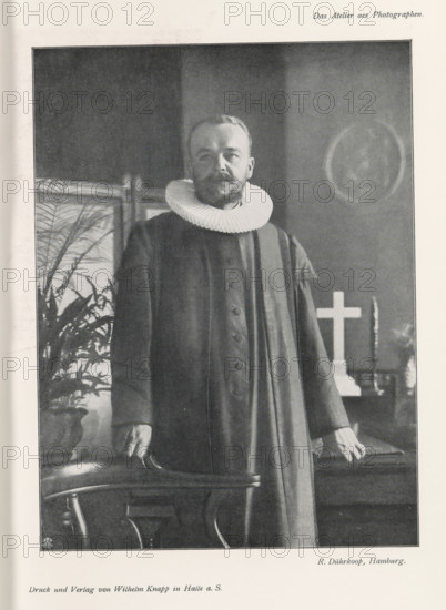 Portrait of an unknown man with collar, page, photomechanical print, inscription: 'Das Atelier aes Photographen.', monogram: 'LEIPZIG, S G', photographer: Rudolf Dührkoop, Hamburg (city), cliché maker: unknown, Leipzig, printer (person): Wilhelm Knapp, Halle an der Saale, c. 1895 - in or before 1900, printer (person), Saxony-Anhalt, Saxony, paper, autotypie, height 201 mm x width 150 mm, historical persons, neck-gear: collar, A black and white portrait of a man standing indoors wearing a dark long robe with buttons down the front and a large pleated white ruff collar, his hands resting on the back of a wooden chair, a potted plant visible behind him to one side, a cross and candlestick on a table in the background, and a circular framed image on the wall.