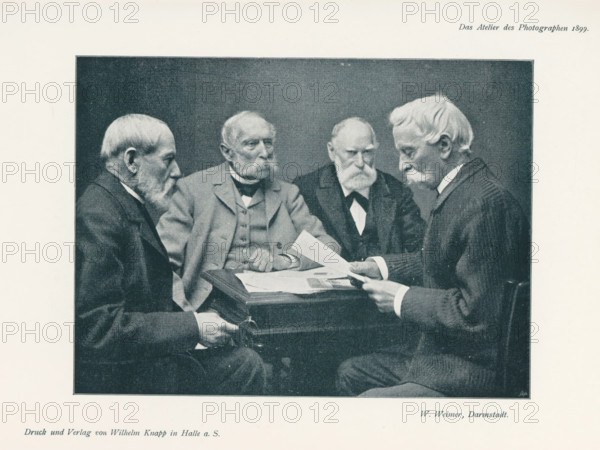 Four men at a table, page, photomechanical print, inscription: 'Das Atelier des Photographen.', photographer: V. de Montano, cliché maker: unknown, printer (person): Wilhelm Knapp, Halle an der Saale, c. 1895 - in or before 1900, printer (person), Saxony-Anhalt, paper, autotypie, height 133 mm x width 180 mm, Print on third unnumbered page after page 124., adult man (four persons), A rectangular black-and-white photograph framed by a light border shows four elderly men seated around a small table holding and looking at papers; all wear suits with jackets and collared shirts, and three have prominent mustaches and beards while one has a mustache and side-parted hair. The man on the far left is shown in profile facing inward, the second man from the left faces slightly toward the camera with folded hands resting on the table, the third man looks down with a stern expression and hands near the papers, and the man on the right holds a sheet of paper and looks at it intently. The table has ...