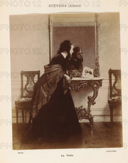 La Visite, Photographic reproduction of a painting of a woman in front of a mirror by Alfred Stevens, photograph, reproduction, page, photographer: Alexandre, after painting by Alfred Stevens, c. 1895 - in or before 1900, paper, daylight gelatin silver print, height 193 mm x width 158 mm, adult woman, reflection (in a mirror) - AA - (for) women (front view), A sepia-toned photograph shows a woman in a dark dress and patterned shawl standing beside an ornate console table with carved legs, leaning forward with one hand resting on the table and her face turned toward a large framed mirror above the table, which reflects her profile and another view of her face; the table top holds a decorative bowl and a folded cloth with a floral arrangement; on either side of the table are upholstered stools with carved wooden frames and lyre-shaped backs against a wall covered in a patterned wallpaper, and the floor beneath is wooden with visible boards.