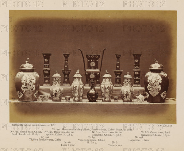 Sixteen objects, including Chinese vases, photograph, page, inscription: 'No. 322. Grand vase, Chine, fon bleu de roi. H. 65 c., ', photographer: Ghémar Frères, c. 1870 - in or before 1875, paper, albumen print, height 122 mm x width 180 mm, container of ceramics: jar, jug, pot, vase, A symmetrical arrangement of ceramic and metal vessels sits on a draped table against a plain dark backdrop, including two large lidded urns with painted floral panels positioned at the outer edges, pairs of tall hexagonal vases with ornate surface decoration set inward from the urns, several lidded baluster-shaped jars with decorative scenes and finial handles across the front, a central tall rectangular vessel with curved handles rising from its sides and floral motifs, smaller cups and a small lidded box placed between the larger pieces, and a narrow foreground strip of lighter surface separating the display from the backdrop.