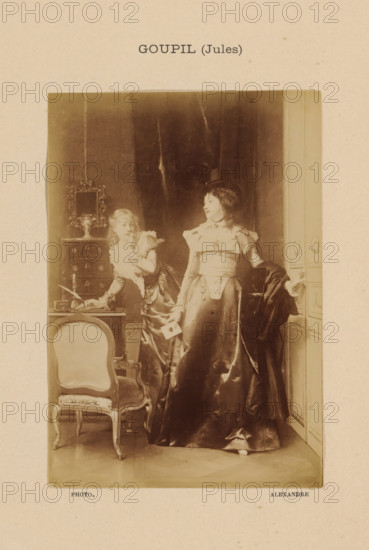 Goupil (Jules), Photo reproduction of La Lettre by Jules Adolphe Goupil, photograph, reproduction, page, photographer: Alexandre, after painting by Jules Adolphe Goupil, c. 1888 - in or before 1893, paper, albumen print, albumendruk, height 144 mm x width 101 mm, adult man, painting, drawing and the graphic arts, A sepia-toned photograph shows two women in elaborate period dresses standing in an interior with paneled walls and heavy drapery. One woman stands facing slightly sideways wearing a long, glossy skirt, a fitted bodice with decorative details, and a small hat, holding a folded card in one hand and a dark cloak draped over her other arm. The other woman leans on a small table while looking toward the first woman; she wears a ruffled collar and a dress with puffed sleeves and is positioned beside a decorative chest topped with an ornate framed mirror and a vase. In the foreground there is an upholstered chair with curved wooden legs and carved details, and the floor shows a patt...